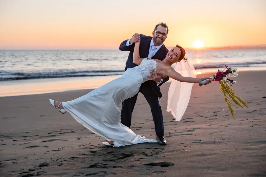 Groom dipping the bride on the beach