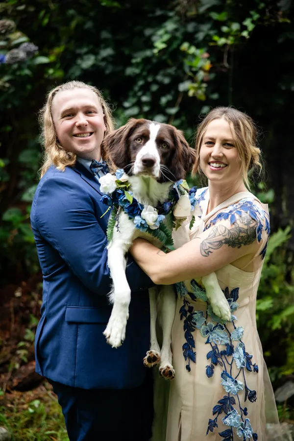 Couple holding their dog on their wedding day