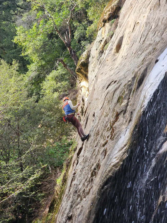 Climber on the rock beside a waterfall